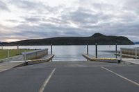 a parking lot with a dock and the mountains in the background and clouds overhead at sunset