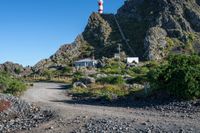 a dirt path and path up to a lighthouse next to a rock face covered mountain