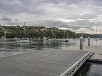 a dock with boats, houses and mountains in the background and clouds hovering above the docks