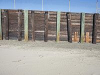 a fence of wooden planks and a metal fence on the beach next to a fence of barbed wire