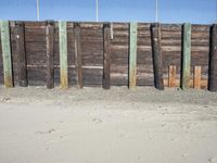 a fence of wooden planks and a metal fence on the beach next to a fence of barbed wire