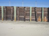 a fence of wooden planks and a metal fence on the beach next to a fence of barbed wire