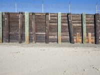 a fence of wooden planks and a metal fence on the beach next to a fence of barbed wire