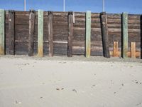 a fence of wooden planks and a metal fence on the beach next to a fence of barbed wire