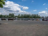 two horses are running near the fenced - in area near the water and a lake