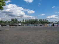 two horses are running near the fenced - in area near the water and a lake