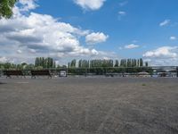 two horses are running near the fenced - in area near the water and a lake