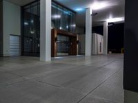 the entrance to an office building with large glass walls and windows at night time to give a feel to someone's surroundings