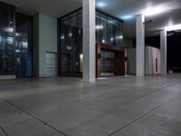 the entrance to an office building with large glass walls and windows at night time to give a feel to someone's surroundings