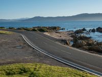 an image of a beautiful beach and coastline road from a hill side perspective at sunset