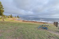 a grassy area near the ocean next to the sand beach with sticks drawn out for carving