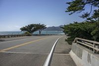 the ocean sits next to an empty road on the shoreline of the island while trees grow along the roadway