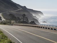 a motorcycle is traveling down the highway on the coast highway near the ocean and cliffs