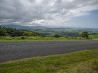 a wide open highway with a view of the hills in the distance and an island in the foreground