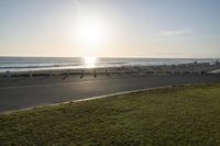 an empty road near a beach and waves as well as cars on the sand and houses on the beach