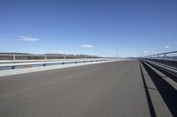 the highway goes straight ahead over the water to the right of the camera and has mountains in the distance