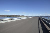 the highway goes straight ahead over the water to the right of the camera and has mountains in the distance