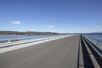 the highway goes straight ahead over the water to the right of the camera and has mountains in the distance