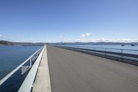 the highway goes straight ahead over the water to the right of the camera and has mountains in the distance