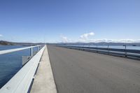 the highway goes straight ahead over the water to the right of the camera and has mountains in the distance