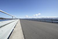 the highway goes straight ahead over the water to the right of the camera and has mountains in the distance