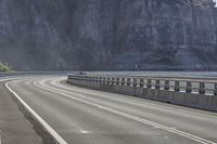 the large rock that wraps all of the sides of a highway has a couple people riding bicycles on it