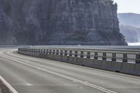 the large rock that wraps all of the sides of a highway has a couple people riding bicycles on it