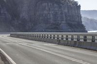 the large rock that wraps all of the sides of a highway has a couple people riding bicycles on it