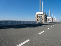 a bridge over the ocean with construction equipment in the background and two people walking on it