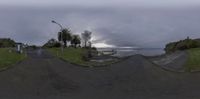 the view of an intersection with a street and a body of water in the background