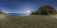 panorama of a small lake by a shoreline under a blue sky with a large white spot