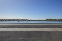 empty paved road with benches beside the edge and a large body of water in the distance