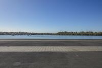 empty paved road with benches beside the edge and a large body of water in the distance