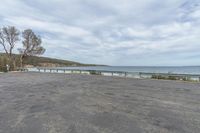 this parking lot has a bench along side the lake and sea with a view in the distance