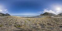 an outdoor scenic landscape view with the beach and mountains as a backdrop from a fish eye lens