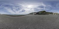 a view of the beach from a fish - eye lens with some clouds in the sky