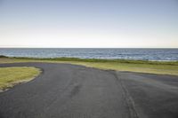 a wide paved road in front of the ocean on a sunny day on an overcast day