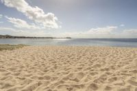 an empty beach on a clear day with some clouds in the distance and a sunny blue sky