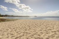 an empty beach on a clear day with some clouds in the distance and a sunny blue sky