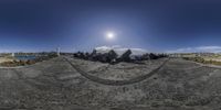 the beach has rock sculptures that appear to be holding something out in the wind in a 360 - lens photo