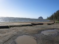 water puddles on the sand and a rocky coast in the distance, there's another body of water next to it