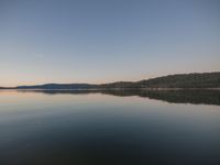 an image of a calm lake during the day and evening time period with no one visible on it