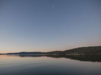 an image of a calm lake during the day and evening time period with no one visible on it