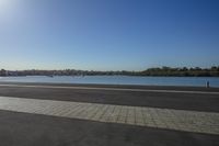 a lone person walking past a lake on a sunny day or a street sign,