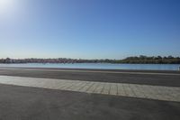 a lone person walking past a lake on a sunny day or a street sign,