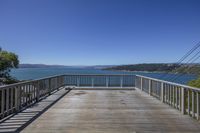 an elevated deck overlooking a bay with mountains and a blue sky in the background,