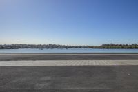 a large body of water in front of trees with a blue sky and small body of water