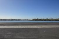 a large body of water in front of trees with a blue sky and small body of water