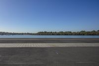 a large body of water in front of trees with a blue sky and small body of water