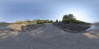 a very wide fisheye view of an island with buildings and rocks, near water